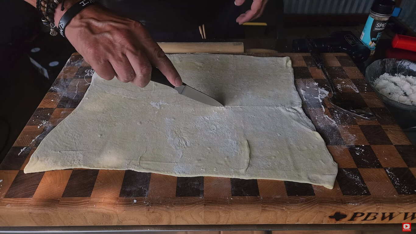 A sheet of puff pastry being cut with a knife